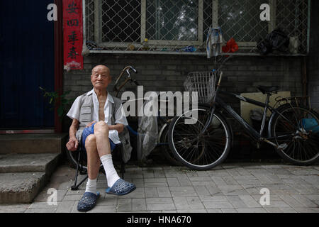 Un homme âgé est assis à l'extérieur d'une propriété dans un hutong, à Beijing, Chine, vendredi 29 juillet, 2016. Les Hutongs sont une labarinth historique de ruelles datant ba Banque D'Images