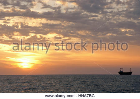 Un bateau de pêche en mer au large de la côte de Chypre au coucher du soleil. Banque D'Images