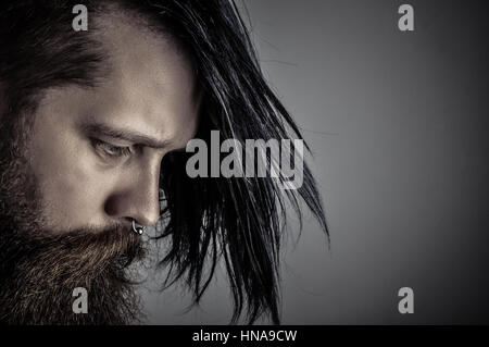 Homme barbu avec de longs cheveux noirs sur fond sombre Banque D'Images