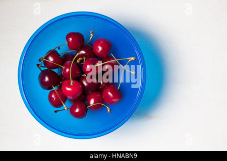 Les cerises dans un bol sur la table de bois blanc. Vue d'en haut Banque D'Images