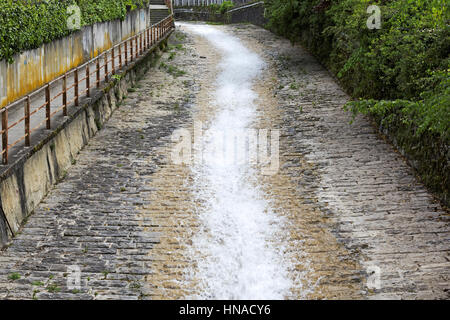 L'eau s'écoule vers le bas à partir du haut d'un jet étroit dans un lit pierreux qui a été construite pour une plus grande quantité d'eau Banque D'Images