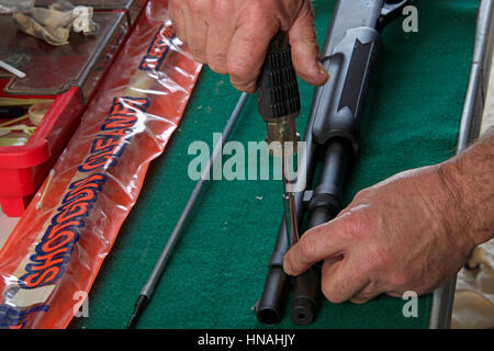 Remplacement d'armurier collier au baril et extension de 20 magazine action pompe jauge de fusil de chasse, à l'aide de tournevis, travaillant sur vert tampon antidérapant Banque D'Images