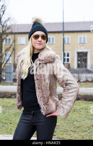 Belle blonde woman fashion femme en manteau de fourrure. L'origine ethnique. scandinave suédois L'hiver et piscine dans paysage de ville. Portant des lunettes de soleil. Banque D'Images