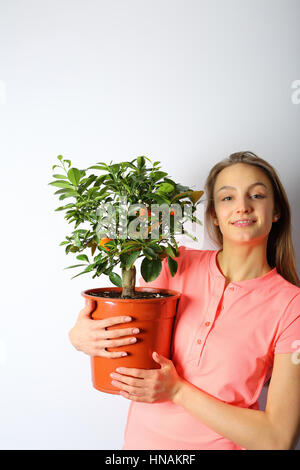 Smiling girl avec un arbre mandarin en main, looking at camera Banque D'Images