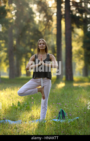 Belle jeune fille debout sur une jambe en yoga pose, mains jointes comme en prière Banque D'Images