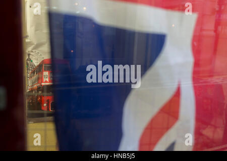Un détail d'une London bus rouge avec London landmarks peeping derrière un drapeau Union Jack britannique chiffonné dans la fenêtre d'un détaillant de la ville, le 2 février 2017, dans la ville de Londres, en Angleterre. Banque D'Images