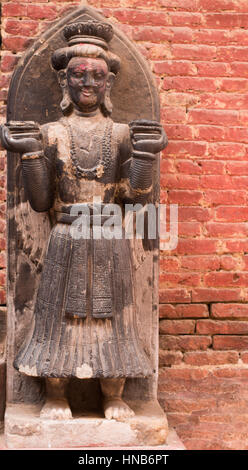 Statue en bois de gardien devant un bâtiment à Bhaktapur, Katmandou, habillée dans le style traditionnel népalais Banque D'Images