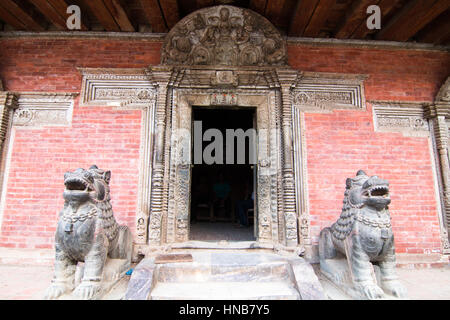 Garde la porte des Lions à l'entrée d'un immeuble ancien avec un linteau en bois finement sculptés dans Bhaktapur, Katmandou, Népal Banque D'Images