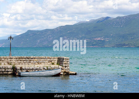 Petit bateau à rames blanche mouillée par la pierre jetée dans le port de lac d'Ohrid, Macédoine Banque D'Images