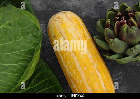 Vue supérieure de légumes fraîchement récoltés, y compris (l-r) le chou, moelle jaune et de l'artichaut contre fond ardoise, Royaume-Uni Banque D'Images