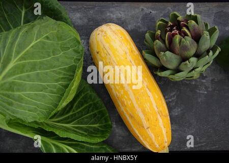 Vue supérieure de légumes fraîchement récoltés, y compris (l-r) le chou, moelle jaune et de l'artichaut contre fond ardoise, Royaume-Uni Banque D'Images