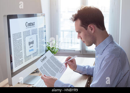Jeune homme d'affaires la signature d'un contrat et la lecture des termes et conditions de l'office. Intérieur moderne avec ordinateur Banque D'Images