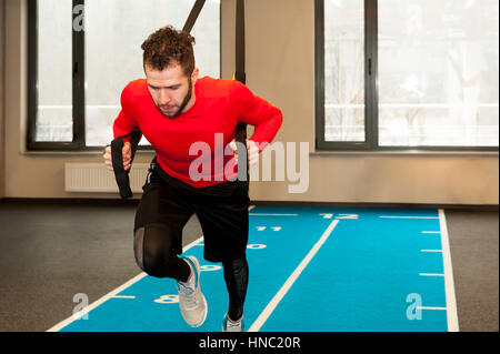 Barbu frisé blanc sporty man exercising with fitness les attaches en salle de sport Banque D'Images