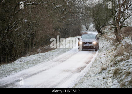 Une voiture passe par des conditions de blizzard avec précaution le long d'une ruelle dans la gamme Clwydian hills dans Flintshire Banque D'Images