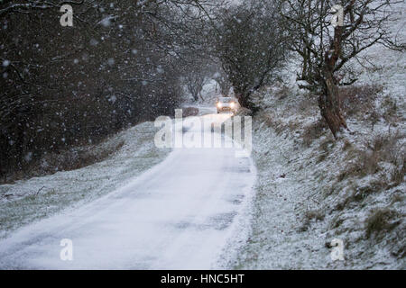 Une voiture passe par des conditions de blizzard avec précaution le long d'une ruelle dans la gamme Clwydian hills dans Flintshire Banque D'Images