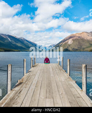 Femme assise sur un quai, vue du lac Rotoiti, Nelson Lakes National Park, district de Tasmanie, Southland, Nouvelle-Zélande Banque D'Images