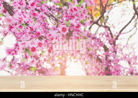 Blooming sakura rose de l'himalaya fleurs de cerisier sauvage sur branch (image flou) avec certains fccus table en bois pour afficher votre produit Banque D'Images