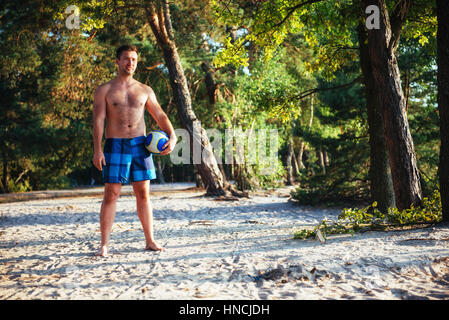 Jeune mec jouer au volleyball sur la plage Banque D'Images