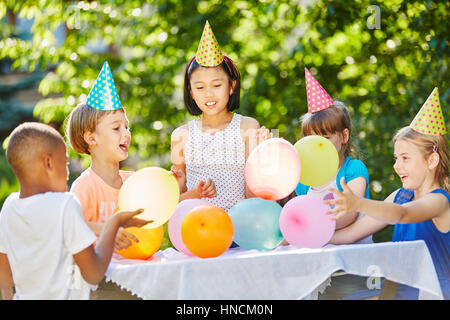 De nombreux enfants célébrer anniversaire avec des ballons et des chapeaux de fête Banque D'Images