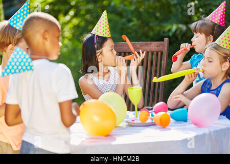 Enfants à l'anniversaire à célébrer ensemble le jardin avec des ballons et des bruits Banque D'Images