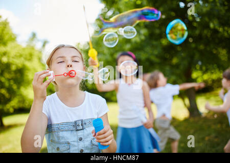 Pour souffler des bulles de savon fragile dans l'air dans le parc en été Banque D'Images