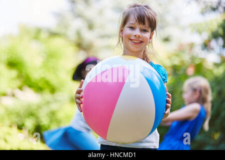 Fille joue avec la balle dans la maternelle en été Banque D'Images