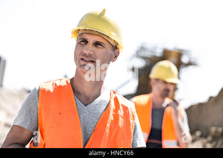 Travailleur homme at construction site avec collègue debout en arrière-plan Banque D'Images