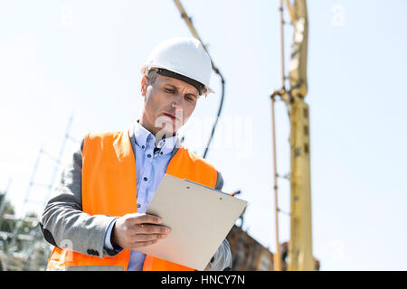 Low angle view of supervisor writing on clipboard at construction site Banque D'Images