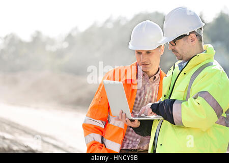 Les superviseurs using laptop at construction site Banque D'Images