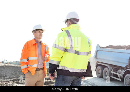 Ingénieurs discuter at construction site contre le ciel clair aux beaux jours Banque D'Images