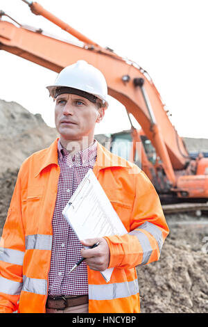 Architecte à la voiture tandis que holding clipboard at construction site Banque D'Images