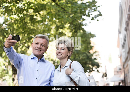 Happy middle-aged couple en tenant l'extérieur selfies Banque D'Images