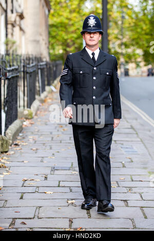 Un policier anglais habillé avec élégance et entièrement uniforme patrouilant sur son rythme, marchant le long d'une rue victorienne à Bath, en Angleterre Banque D'Images