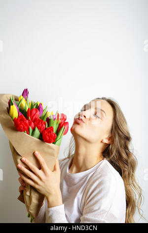 Fille avec les baisers des lèvres, tenant un bouquet de fleurs, les yeux fermés Banque D'Images