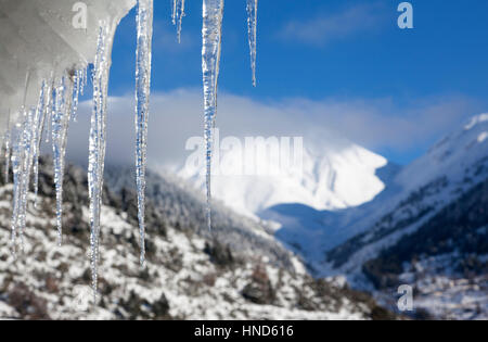 Stalactites temporelle suspendue à un toit de tuiles, en un jour de neige en plein milieu de l'hiver, dans des régions montagneuses de la Grèce. Banque D'Images