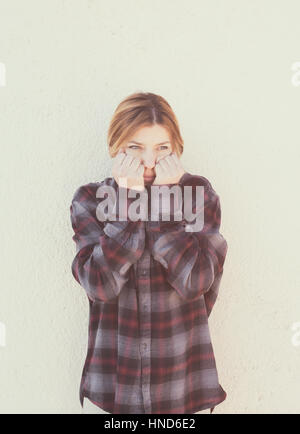 Jeune femme avec les mains sur le visage dans un style rétro portrait concept de honte et de timidité, vertical vintage retro style effet couleur Banque D'Images