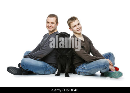 Portrait de famille. Avec l'âge de l'adolescence père fils assis sur marbre noir avec Shar Pei chien. Isolé sur fond blanc. Copier l'espace. Banque D'Images