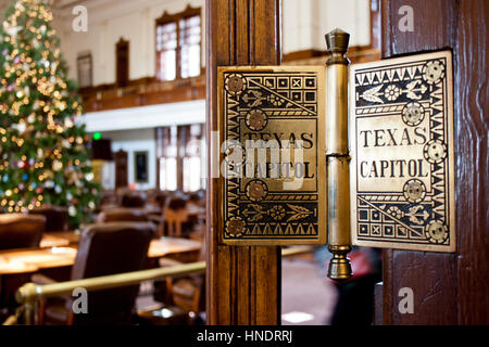 Un détail d'une charnière de porte dans le Texas State Capitol building avec un arbre de Noël illuminé en arrière-plan. Banque D'Images