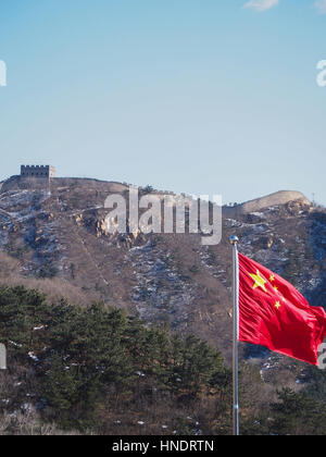 Un drapeau chinois rouge vif vagues en face de la Grande Muraille de Chine. Banque D'Images