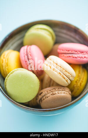 Délicieux macarons sucré dans un bol. Les macarons sur fond bleu. Banque D'Images