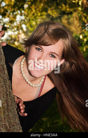 Une teen girls peeks autour d'un arbre Banque D'Images