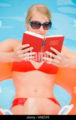 Communiqué de modèle, Junge Frau beim Lesen im piscine d'- Woman Reading in swimming pool Banque D'Images