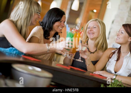 Communiqué de modèle, Vier junge Frauen mit sitzen an der Bar cocktails - quatre femmes dans un bar à cocktails Banque D'Images