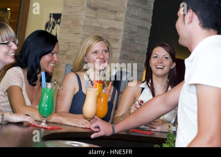 Communiqué de modèle, Junger Kellner flirtet mit vier Frauen an der Bar - barman coquets avec quatre femmes au bar Banque D'Images