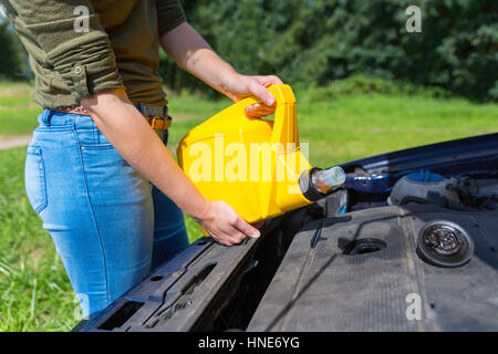 Young caucasian woman voiture de remplissage avec de l'huile moteur en bidon jaune Banque D'Images