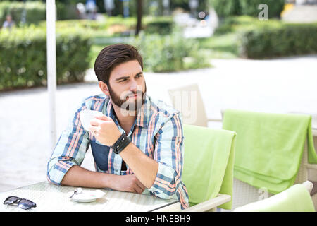 Thoughtful man holding Coffee cup at sidewalk cafe Banque D'Images