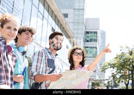 Heureux avec des amis de route avec la femme en pointant à l'écart dans la ville Banque D'Images