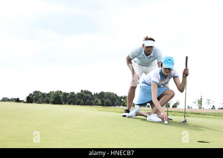 Homme avec femme visant ball on golf course contre le ciel Banque D'Images