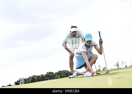 Mid-adult man looking at woman visant ball on golf course Banque D'Images