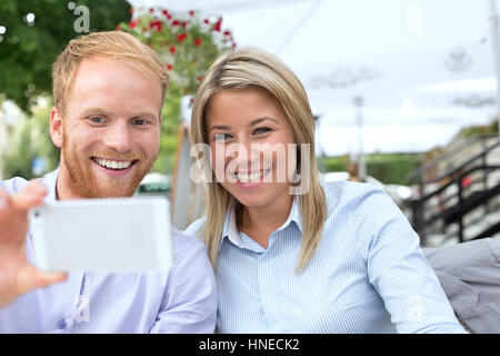 Happy business couple at outdoor restaurant selfies Banque D'Images